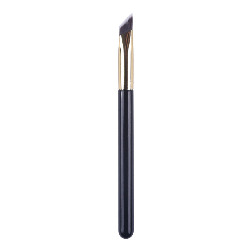 An angled eyebrow brush with dark bristles, a gold metal ferrule, and a sleek black handle against a white background.