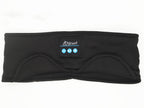 Black fabric Bluetooth sleep headband with integrated control panel, music playback buttons, and eye mask contour.