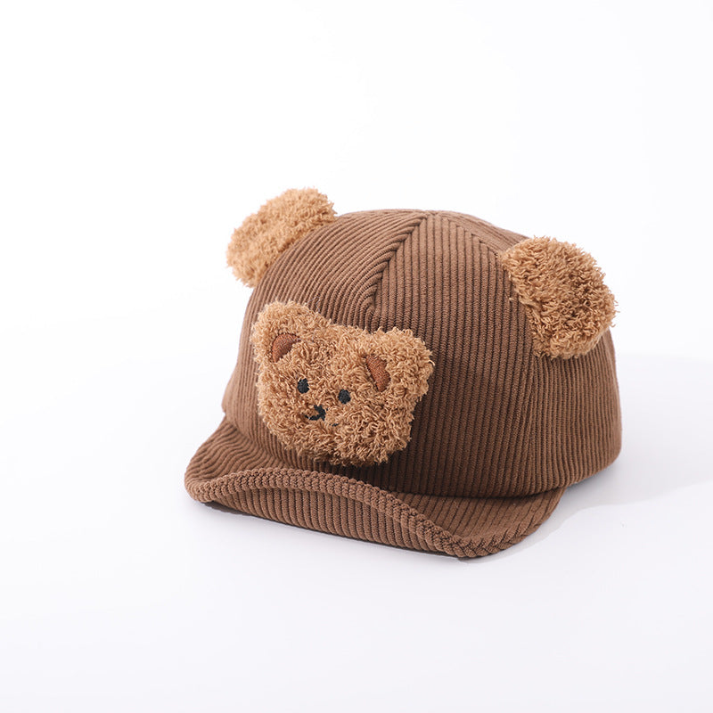 Brown corduroy baby hat with fuzzy bear ears and a plush teddy bear face patch, featuring a curved brim.