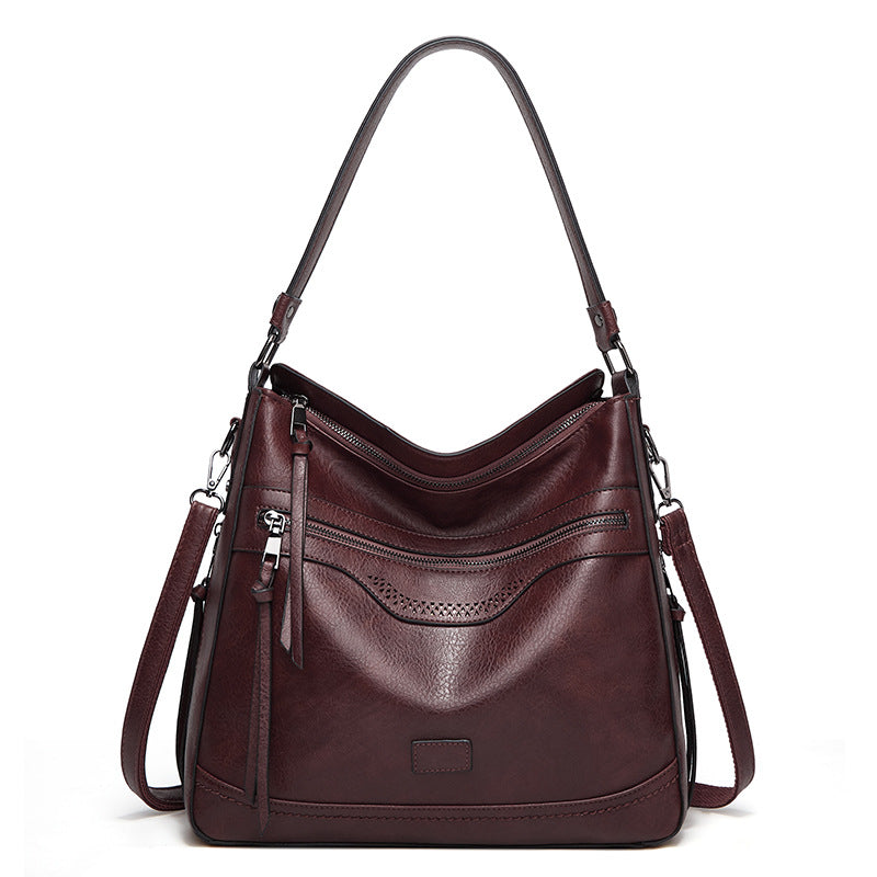Dark burgundy, soft leather vintage tote bag with zippered pockets, silver hardware, and a single shoulder strap.