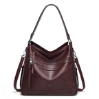 Dark burgundy, soft leather vintage tote bag with zippered pockets, silver hardware, and a single shoulder strap.