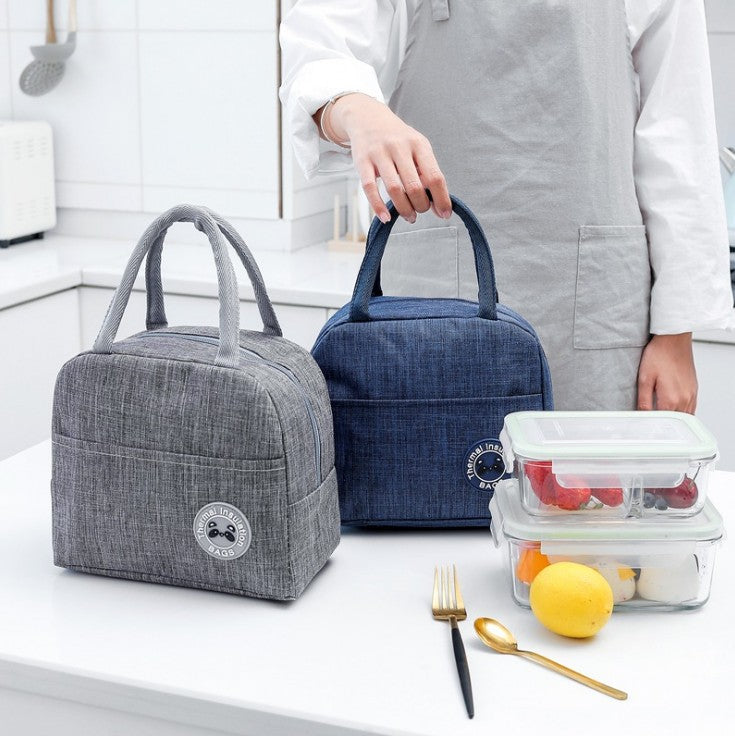 Grey and navy cationic fabric thermal lunch bags with handles, shown on a white surface next to food containers.