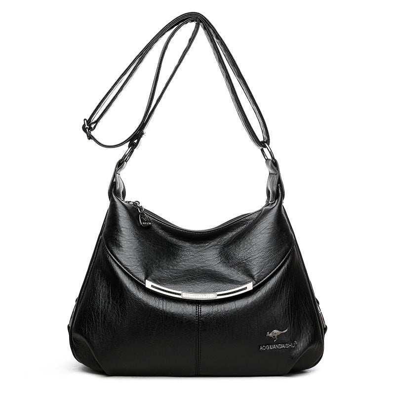 Black soft leather shoulder bag with adjustable strap, curved silver metal accent, and metallic kangaroo logo emblem.