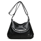 Black soft leather shoulder bag with adjustable strap, curved silver metal accent, and metallic kangaroo logo emblem.