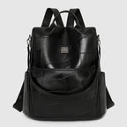 Black leather-look backpack with a minimalist patchwork design, dual straps, and metallic logo plate.