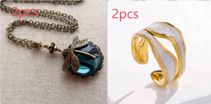 A dragonfly pendant necklace and an open, gold-tone titanium steel ring with wavy white enamel detailing.