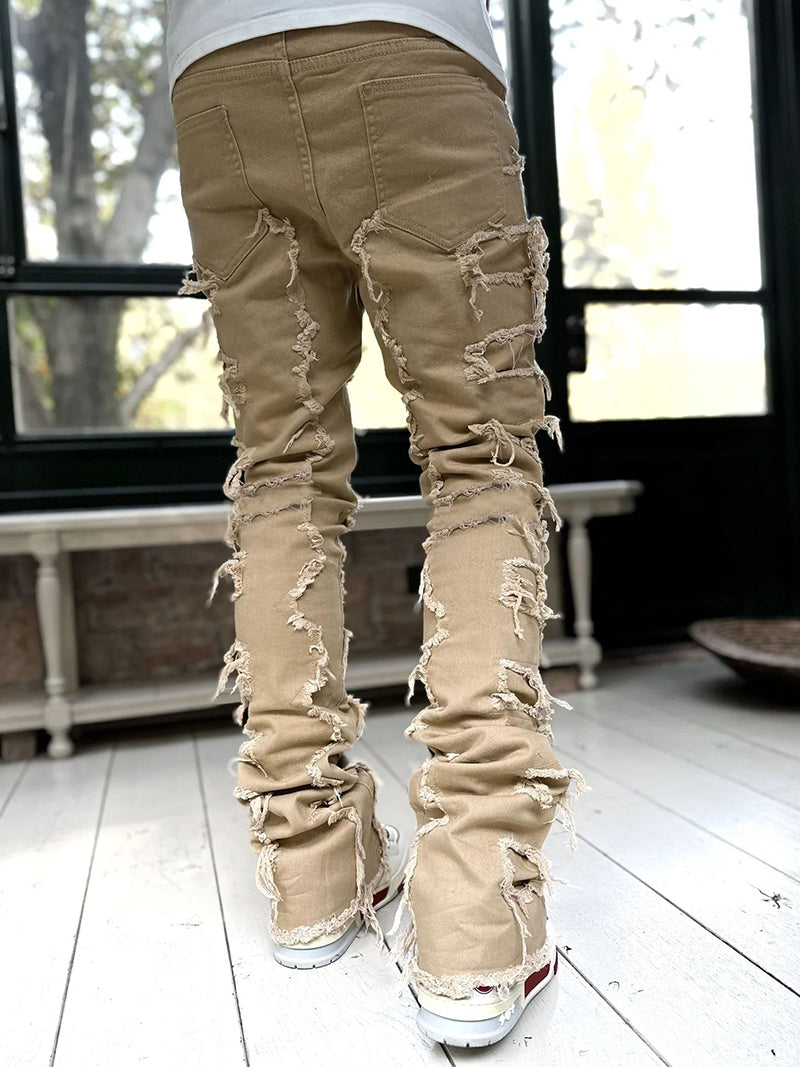 Tan, stacked-fit denim trousers for men featuring distressed, raw-edge fringe details along the legs.