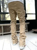 Tan, stacked-fit denim trousers for men featuring distressed, raw-edge fringe details along the legs.