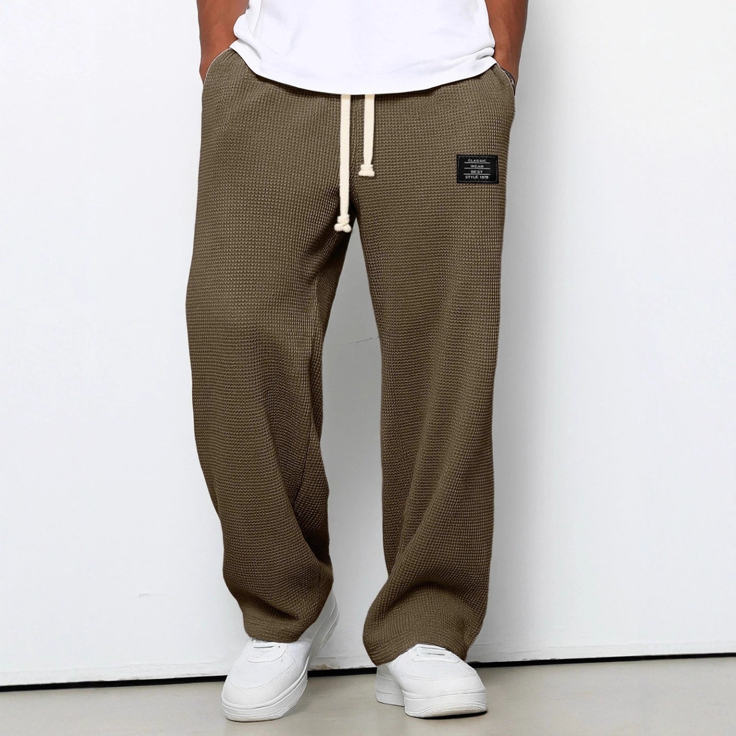 Olive green waffle-knit straight pants with a white drawstring waist, relaxed fit, and small rectangular patch label.