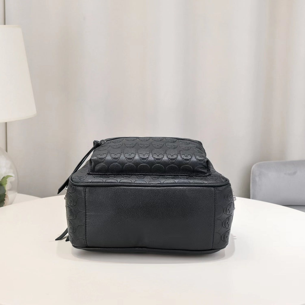 Black soft leather backpack with an embossed skull pattern and silver rivet accents on a white table.