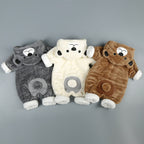 Three plush, fleece baby onesies in gray, cream, and brown, featuring bear hoods and cute belly patches.