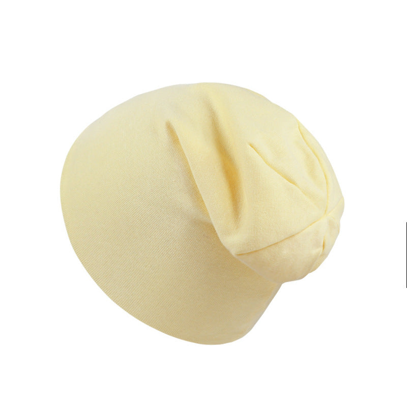 A soft, light yellow jersey-knit newborn beanie with a simple, slouchy, hexagon-style design on a white background.
