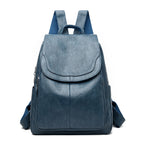 Blue leather-look women's travel backpack with a fold-over flap, side pockets, and durable webbed straps.