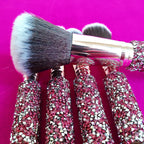 Makeup brushes with pink rhinestone-inlaid handles, gold ferrules, and soft, two-tone black and white synthetic bristles.