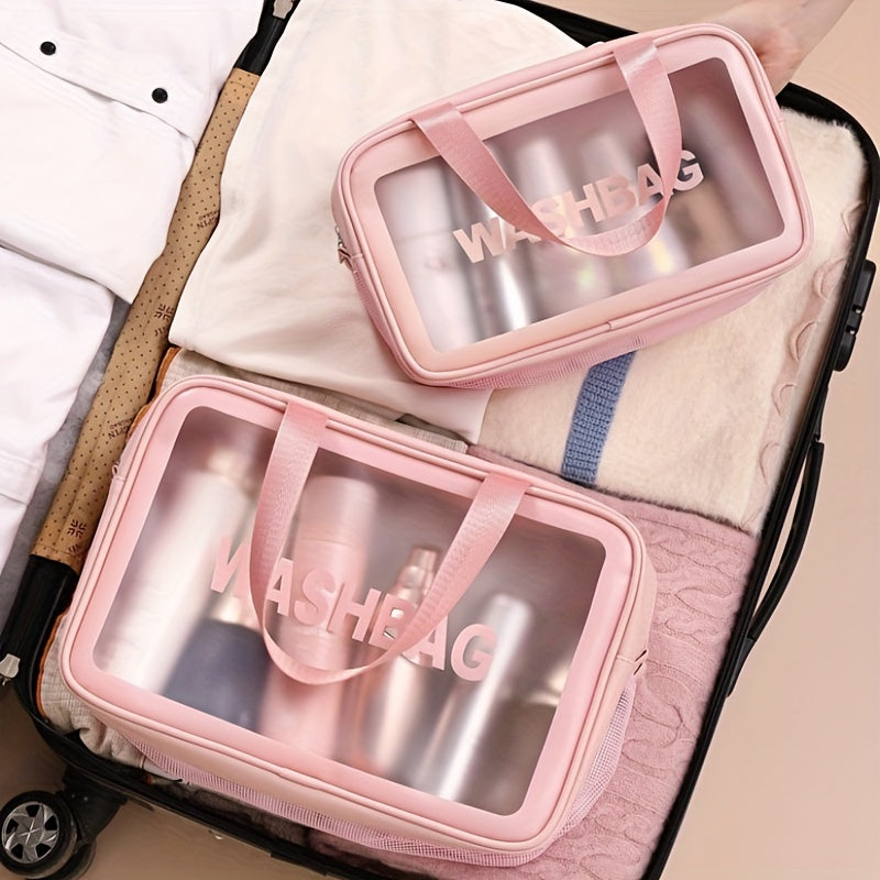 Two pink, clear-windowed "WASHBAG" travel organizers packed inside a suitcase with clothing.