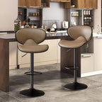 Two tan, curved faux-leather bar stools with black metal pedestals and footrests in a modern kitchen.