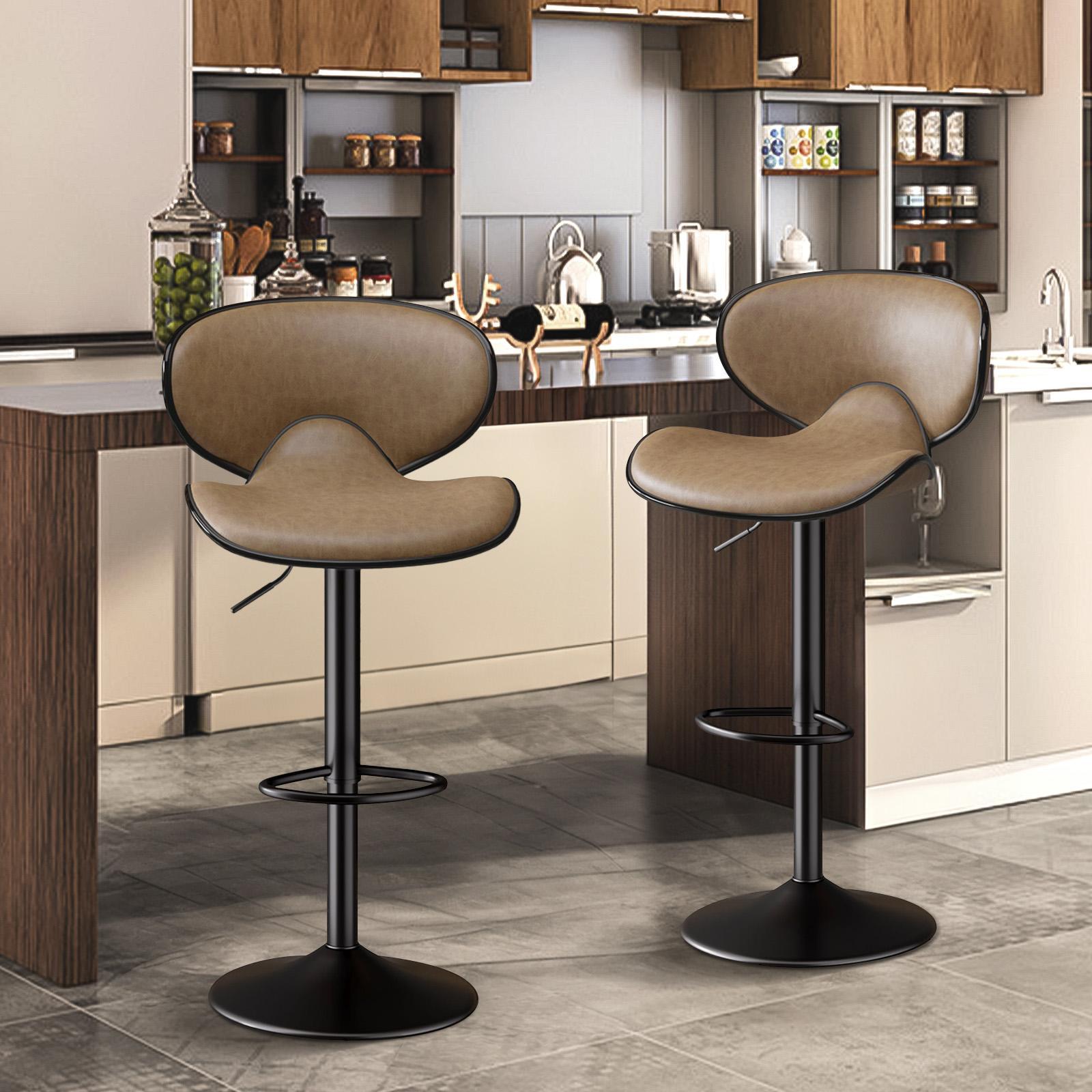 Two tan, curved faux-leather bar stools with black metal pedestals and footrests in a modern kitchen.