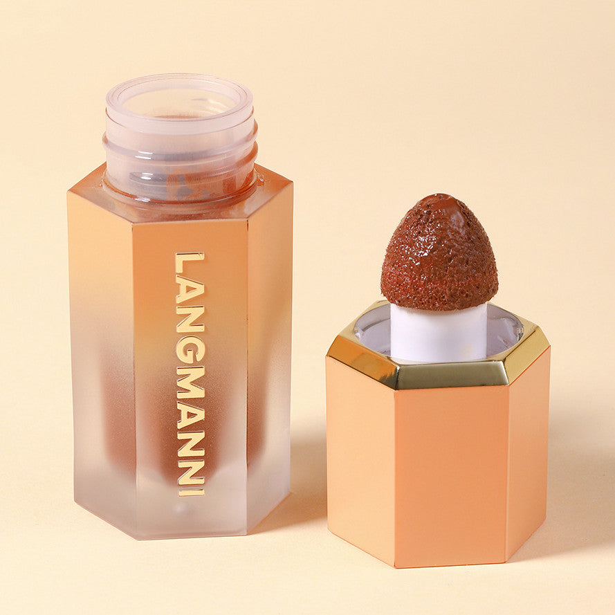 Langmanni liquid contour bottle in hexagonal glass with peach-colored cap and sponge applicator.