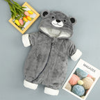 Gray plush baby onesie with bear-eared hood, white cuffs, and zipper closure, displayed on a flat surface.