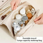 Beige travel makeup bag being opened, filled with various cosmetic bottles, brushes, and toiletries.